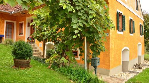 una casa con un árbol delante de un edificio en Bauernhaus Posch, Ferienappartements, 