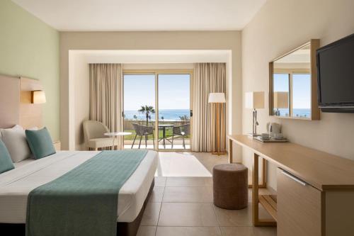 een hotelkamer met een bed en uitzicht op de oceaan bij Ramada Hotel & Suites by Wyndham Ayia Napa in Ayia Napa