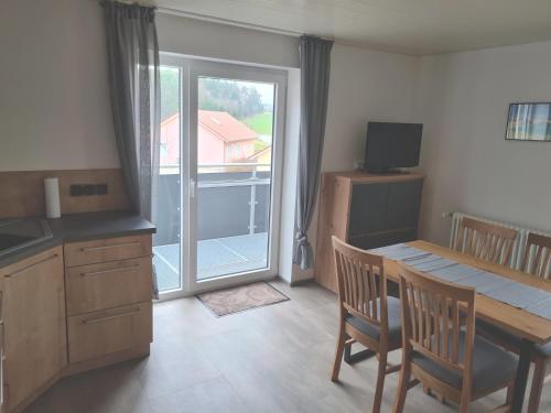 a kitchen with a table and chairs and a balcony at Pension Zum Grünen Wald in Feuchtwangen