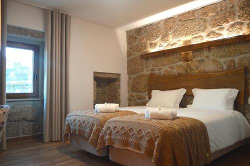 a bedroom with a large bed with a stone wall at Quinta do Limite - Agroturismo in Covilhã