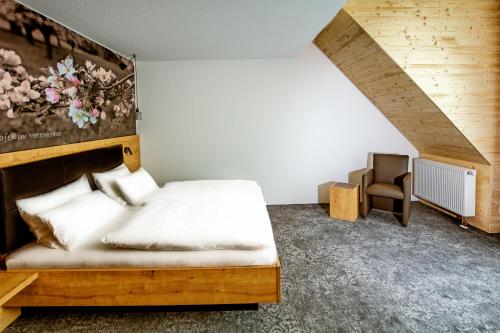1 dormitorio con cama de madera y silla en Ringhotel sKreuz, en Steinheim am Albuch