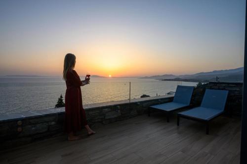 a woman standing on a ledge looking at the sunset at Mani Suites luxury seaside accommodation in Agios Nikolaos