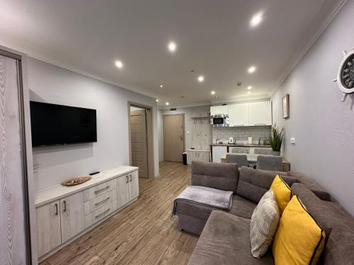 a living room with a couch and a flat screen tv at Maximus Apartamenty in Ustka