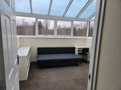 1 Bedroom en suite ASHLAND, Milton keynes في Fenny Stratford: غرفة مع مقعد في غرفة مع نوافذ