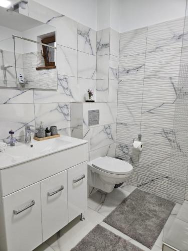 a white bathroom with a toilet and a sink at Tei Residence in Piatra Neamţ