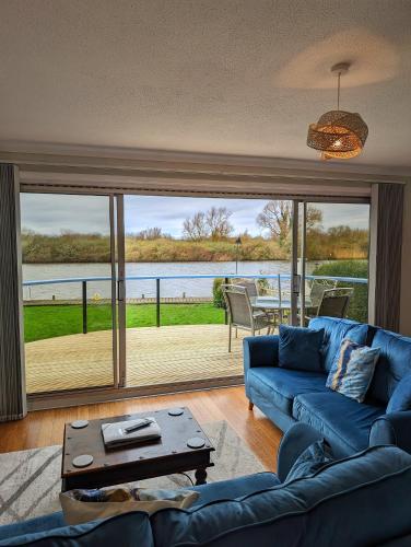 a living room with a blue couch and a large window at River View - Norfolk Broads in Brundall