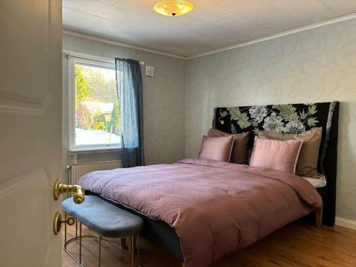 a bedroom with a bed with a purple comforter and a window at 3BDR close to nature a beautiful home LAKE nearby in Uppsala