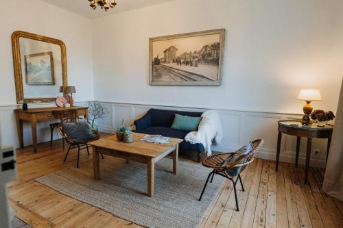 uma sala de estar com um sofá azul e uma mesa em La Maison Pelloquin em Bernières-sur-Mer
