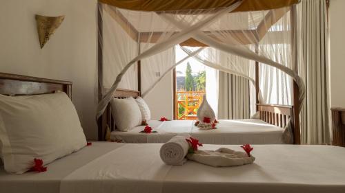 a bedroom with two beds with red ribbons on them at Nungwi Garden Boutique Hotel in Nungwi