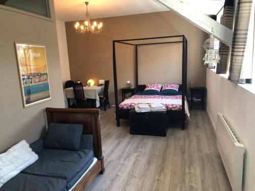 1 dormitorio con cama, sofá y mesa en Chambre et Petit-déjeuner à Collonges au Mont d'Or en Collonges-au-Mont-dʼOr
