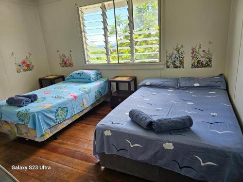 a bedroom with two beds and a window at Heleni Jessop's Fatahega in Alofi