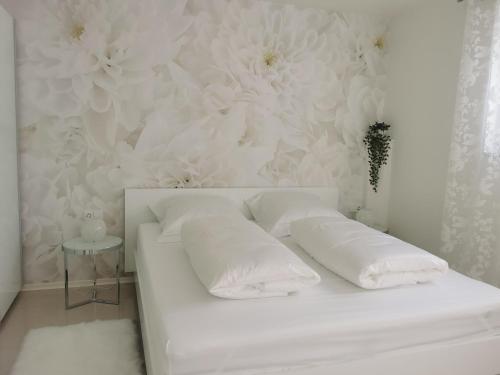 ein weißes Bett mit Kissen und eine Wand mit Blumen in der Unterkunft Ferienwohnung Edelweiß in Rust
