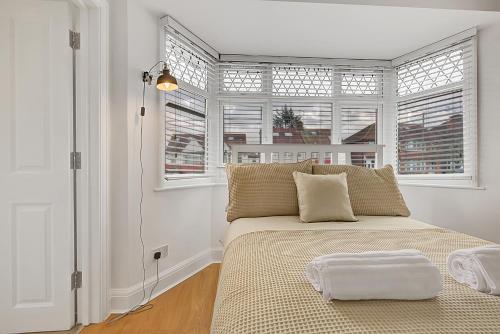 um quarto com uma cama e duas janelas em Quality Apartments Close to Tube em Hendon