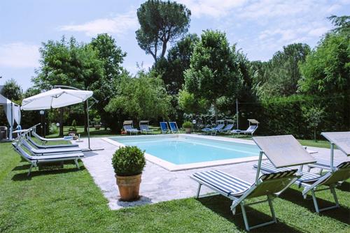 a swimming pool with chairs and a table and an umbrella at Casa Capanni alla Fila in Cortona