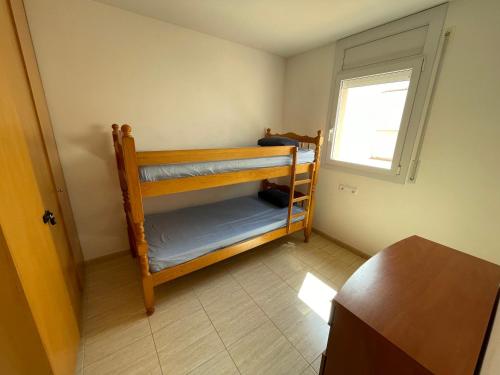 ロザスにあるNorfeu Parkの二段ベッド2台、窓が備わる小さな客室です。