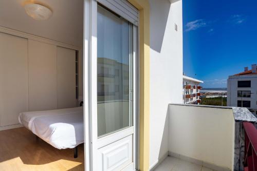 balkon z łóżkiem i szklanymi drzwiami w obiekcie Peniche Sun & Surf Apartment w mieście Peniche