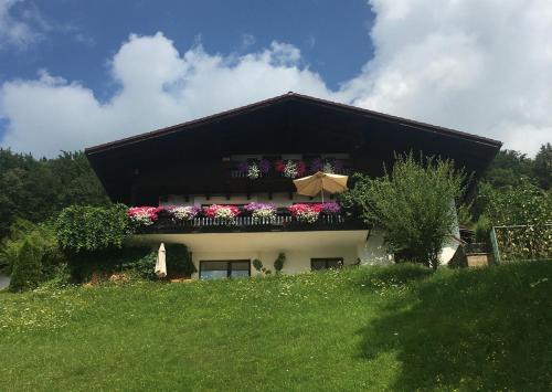 ein Haus mit einem Balkon mit Blumen und einem Sonnenschirm in der Unterkunft Angela Siedl in Ebenau