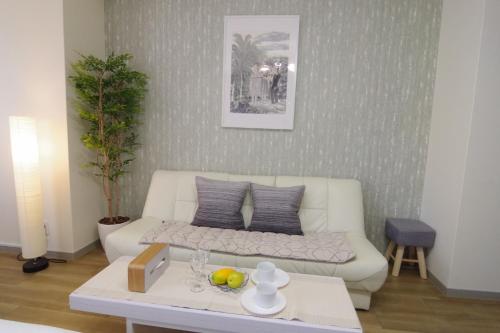 uma sala de estar com um sofá branco e uma mesa em Matsuyamachi Shimanouchi Building - Vacation STAY 14368 em Osaka
