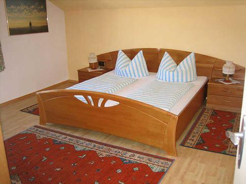 a bedroom with a wooden bed with blue and white pillows at Apart Sonneck in Arzl im Pitztal