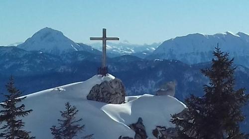 a cross on top of a mountain with snow at Bocksleitnerhof in Wackersberg