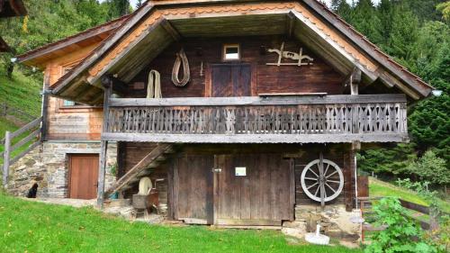 an old wooden cabin with a balcony and a wheel at Feldkasten Biohof Lurger in Breitenbrunn