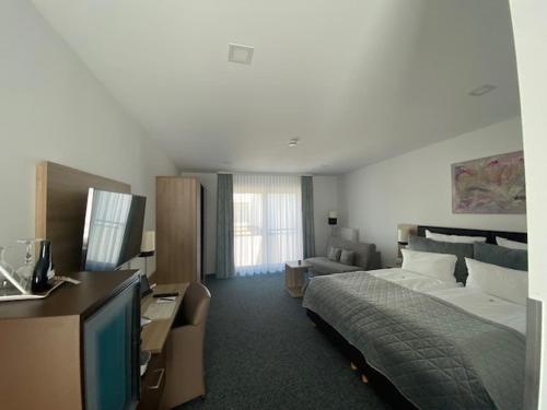 a bedroom with a bed and a television and a couch at Stadthotel Geis in Bad Neustadt an der Saale