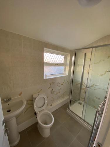 a bathroom with a toilet and a shower and a sink at 121 Spring Road in Kempston