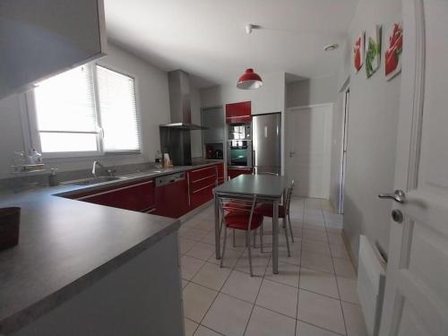 a kitchen with red cabinets and a table with chairs at Villa de Caractère in Pourcieux