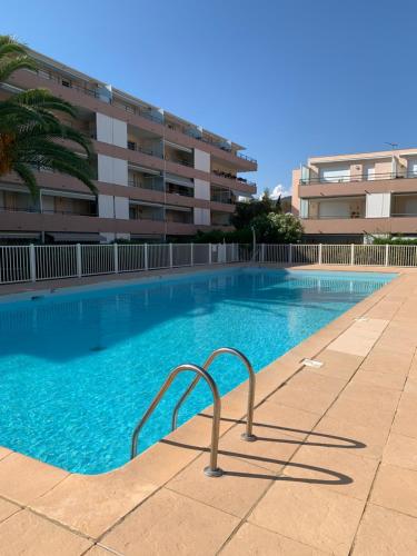 une piscine devant un immeuble dans l'établissement appartement résidence riviera avec piscine, au Lavandou