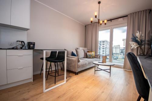 eine Küche und ein Wohnzimmer mit einem Sofa und einem Tisch in der Unterkunft InPoint Tauron Arena Apartment with Parking - Lema 17 in Krakau