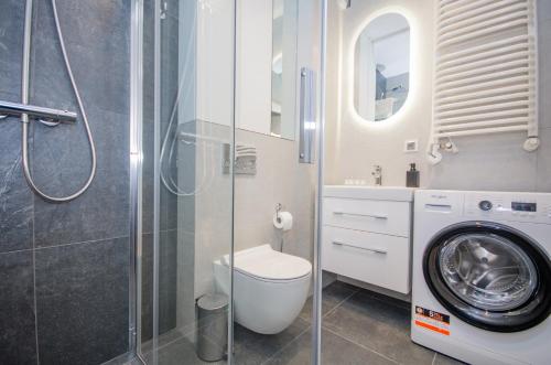 ein Badezimmer mit einem WC und einer Waschmaschine in der Unterkunft InPoint Tauron Arena Apartment with Parking - Lema 17 in Krakau