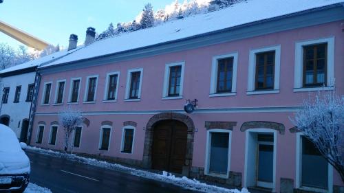 a pink building with a door in the snow at Ferienwohnungen Manuela in Schottwien
