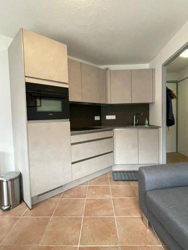 une cuisine avec des armoires blanches et un canapé dans une pièce dans l'établissement Resort central apartment ideal for up to 2 people, aux Carroz d'Arâches