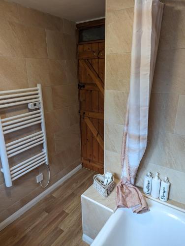 a bathroom with a tub and a shower curtain at Jasmine Cottage Lastingham North Yorkshire in Lastingham