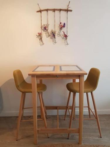 une table en bois avec deux chaises à côté d'un mur dans l'établissement Les Valéricaines - Studio en plein cœur de la cité médiévale, à Saint-Valery-sur-Somme