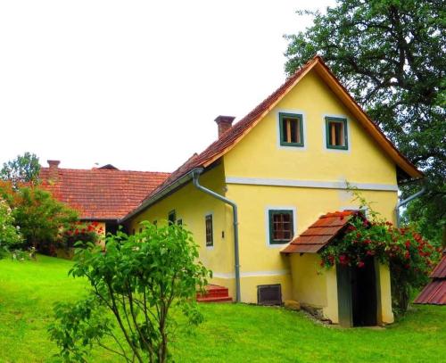 a yellow house with a red roof on a green yard at Ferienhaus Baumgarten1 in Gnas