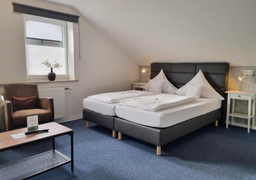 a bedroom with a large bed and a chair at Hotel Dat greune Eck in Soltau