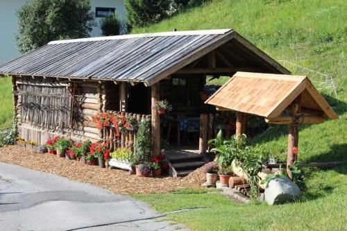 a small house with a wooden roof and flowers at Bauernhof Huber in Wenns