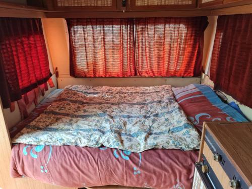 - un lit au milieu d'une chambre avec fenêtres dans l'établissement Jolie caravane à SÏvåñă Oasis de Lumière, à Tourves