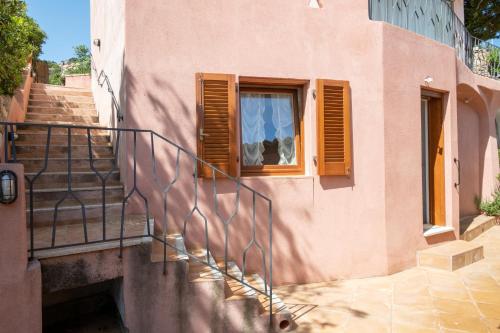 a pink building with a staircase and a window at [CALA DI VOLPE] Vista Mare e Piscina in Abbiadori