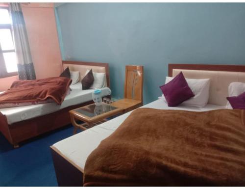 a hotel room with two beds and a table at HOTEL HIMGIRI, Shri Badrinath in Badrinath