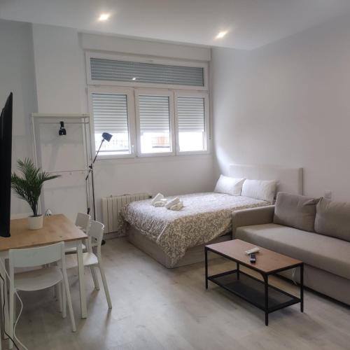 Sala de estar con cama, sofá y mesa en DH Estudios Lopez de Hoyos, en Madrid