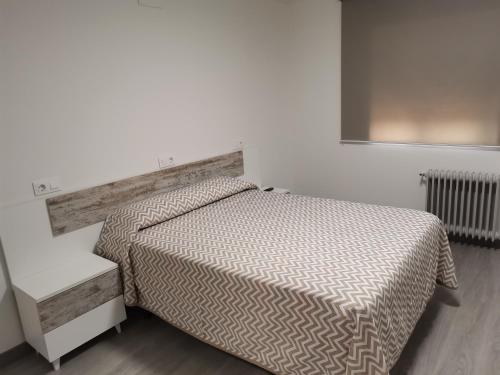 1 dormitorio con cama y pared blanca en hostal san francisco, en Puebla de Sanabria