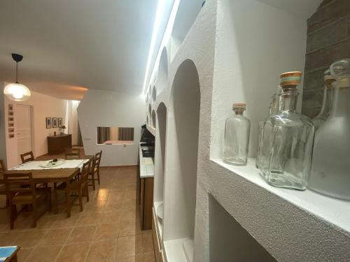 a kitchen and dining room with glass bottles on a shelf at La noce spaccata, casa vacanze in Macchia dʼIsernia