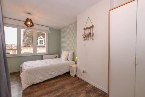 ein kleines Schlafzimmer mit einem Bett und einem Fenster in der Unterkunft Les Valéricaines - Bel appartement - vue sur les toits de St Valéry in Saint-Valery-sur-Somme