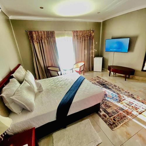 a bedroom with a bed and a flat screen tv at Rosenia Boutique Hotel_Block 3 in Gaborone