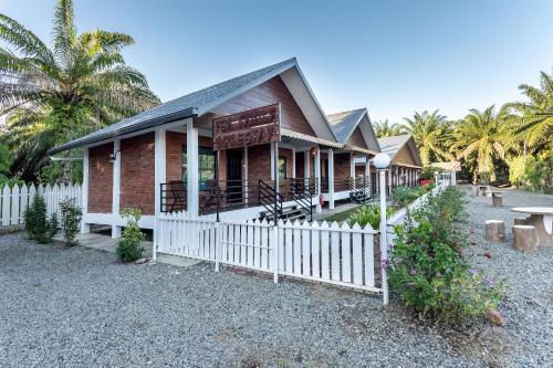 a house with a white fence in front of it at OYO 90149 Pua Family Semporna in Semporna