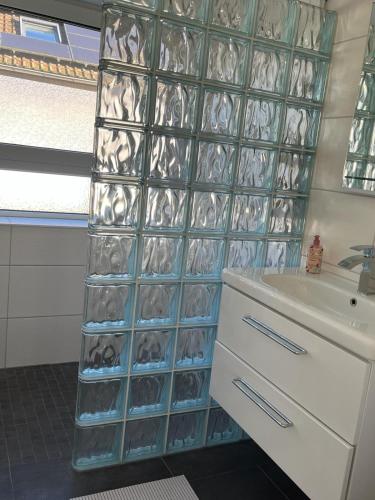 a bathroom with a wall of clear glass containers next to a sink at Ferienwohnung in Sinzheim bei Baden Baden für 1- 6 Personen in Sinzheim
