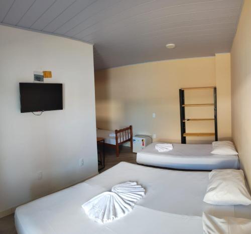 2 camas en una habitación con TV en la pared en Do Parque Pousada Comfort en Penha