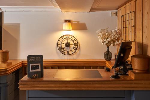 a desk with a book and a clock on the wall at Rashleigh Arms in St Austell